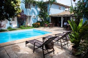 una piscina con sillas y mesas y una casa en Villa Salvia Geriba Beach ao lado Fishbone, en Búzios