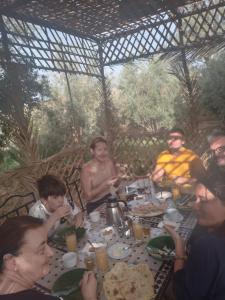 een groep mensen die rond een tafel zitten te eten bij Gîte Ait lmaalam chez Ahmed in Skoura