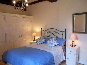 a bedroom with a blue bed with two lamps and a mirror at Tranquil Cottage in Normandy in Sainte-Marguerite-dʼElle