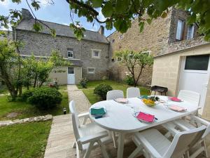 Stone house typical of the Pays de Rance, 900m from the beach في Le Minihic-sur-Rance: طاولة بيضاء مع كراسي بيضاء في حديقة