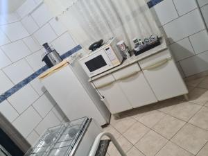 a small kitchen with white cabinets and a microwave at Ap aconchegante bq in Barbacena