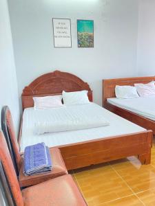 a bedroom with two beds and a chair at Homestay An An in Vung Tau