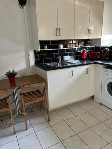 a kitchen with white cabinets and a sink and a table at London City Apartment in London