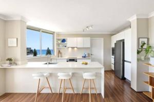 a kitchen with a large white island with bar stools at SeaDreams Beachfront Manly in Manly 