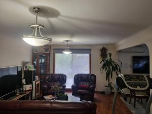 Tani Family home في Rowville: غرفة معيشة مع كرسيين جلديين وأريكة