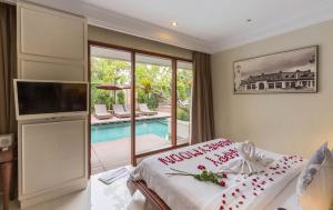 a bedroom with a bed and a tv and a pool at Seminyak Lagoon All Suites Hotel in Seminyak