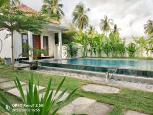 a villa with a swimming pool in front of a house at torok ocean homestay in Mataram