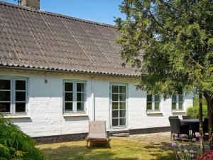 a white house with a chair in the yard at Holiday home Rønne VI in Rønne