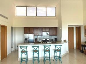 a kitchen with a bar with four stools at Disfruta hermosa vista al mar! in San Carlos