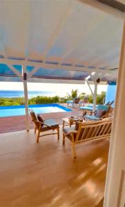 - une terrasse couverte avec des chaises, une table et une piscine dans l'établissement La Villa By Ferdi'Nan, à Grand-Bourg