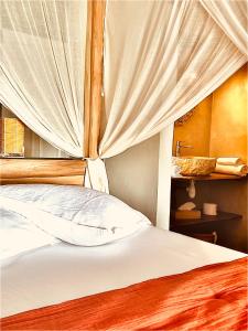 Grand-BourgにあるLa Villa By Ferdi'Nanのベッドルーム1室(白いシーツとカーテン付きのベッド1台付)