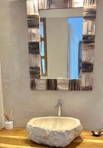 a bathroom with a large stone sink and a mirror at La Villa By Ferdi'Nan in Grand-Bourg