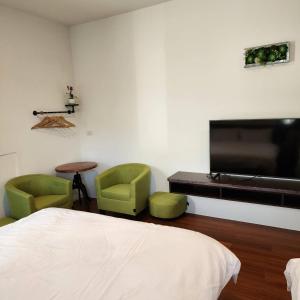 a bedroom with two green chairs and a flat screen tv at Hajin Homestay in Puli