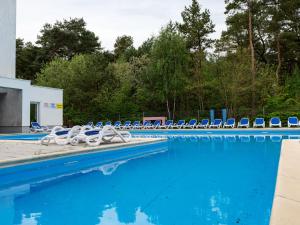 a swimming pool with blue and white lounge chairs at Duplex, spacious holiday apartment, summer swimming pool, Pogorzelica in Pogorzelica