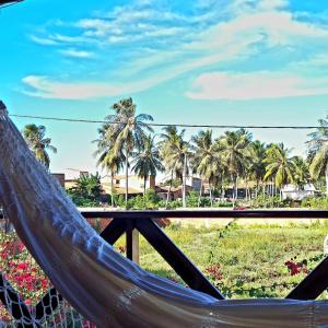 a hammock with palm trees and a field of flowers at Suítes Bosque de Flecheiras in Flecheiras