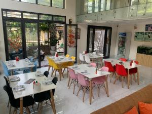 a restaurant with white tables and colorful chairs at John Peter House in Sầm Sơn