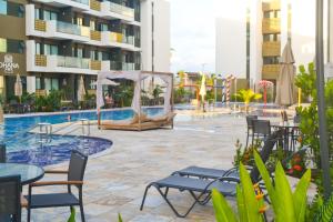 ein Hotelpool mit Stühlen und Tischen und einem Zelt in der Unterkunft MANA BEACH EXPERIENCE PORTO DE GALINHAS in Porto De Galinhas + 19 Fotos