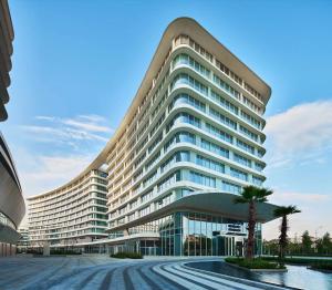 een groot gebouw met een palmboom ervoor bij HongQiao Primus Residence Apartment - National Exhibition Center in Shanghai