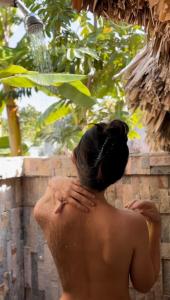 a woman sitting in a shower with her hands on her head at Villa el Oasis, luxurious Santa Marta getaway in Santa Marta