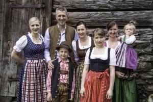 a family posing for a picture in front of a cabin at Alpengasthof Karalm in Rauris