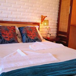 Una cama con sábanas blancas y almohadas en un dormitorio en Suítes Bosque de Flecheiras en Flecheiras