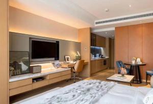 a bedroom with a bed and a desk with a television at HongQiao Primus Residence Apartment - National Exhibition Center in Shanghai