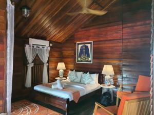 - une chambre avec un lit dans une pièce dotée de murs en bois dans l'établissement Melina Beach Resort, à l'Île Tioman