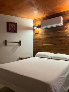 a bedroom with a white bed and a fan at Malakai Hostel in Tulum