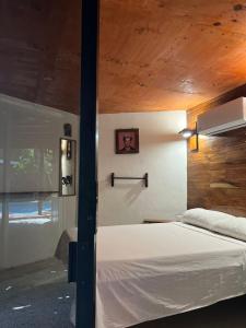 a bedroom with a white bed with a wooden ceiling at Malakai Hostel in Tulum