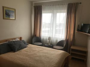 1 dormitorio con 1 cama, 2 sillas y ventana en Pilaites svetingi namai, en Vilna