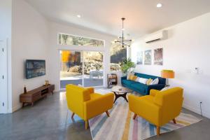 Eagle Rock Nest ～Quiet & Gorgeous Mountain Views في ثري ريفرز: غرفة معيشة مع كراسي صفراء وأريكة زرقاء