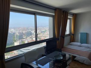 Zimmer mit einem Schreibtisch, einem Bett und einem Fenster in der Unterkunft Grand Studio à la Défense in Courbevoie