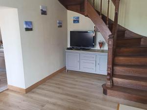 ein Wohnzimmer mit einem TV und einer Treppe in der Unterkunft Gîte familial à la ferme avec activités nature - FR-1-489-454 in La Chabanne