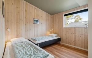 two beds in a room with wooden walls and a window at Cozy Home In Nex With Kitchen in Snogebæk