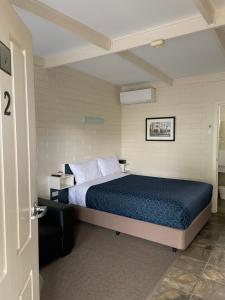 a bedroom with a bed with a blue comforter at Central Highlands Motor Inn in Kyneton