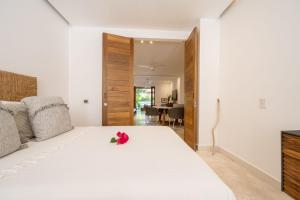 - une chambre avec un grand lit blanc orné de fleurs dans l'établissement El Careyes Club & Residences, à Careyes