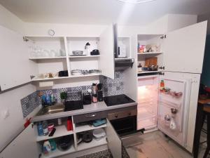 una cucina con armadi bianchi, lavandino e frigorifero di Grand Studio à la Défense a Courbevoie