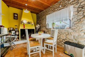 a kitchen with a table and chairs and a stone wall at Holiday house with a swimming pool Smokvica, Korcula - 9297 in Smokvica