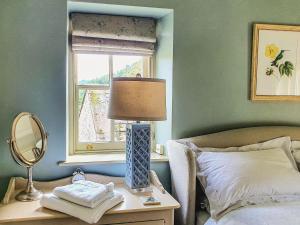 a bedroom with a bed with a lamp and a window at Penny Cottage in Bonsall