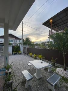 un patio con una mesa blanca y dos bancos en Homestay Aalaiya Bertam Kepala Batas - Fully Aircond, en Kepala Batas