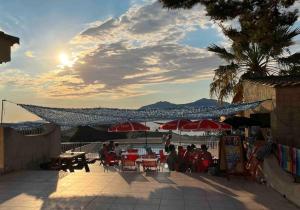 a group of people sitting at tables under red umbrellas at Charmant 2 pièces avec vue sur mer à Porticcio en Corse du Sud in Porticcio