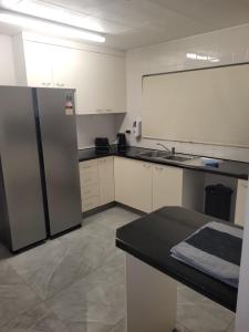 a kitchen with a stainless steel refrigerator and a sink at Paradise Holiday Apartments in Cairns