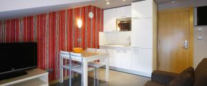 a kitchen with a small white table and a television at Apartamentos Spa Cueto in Cangas de Onís