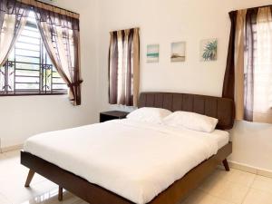 a bedroom with a large bed with white sheets and windows at Nestle Homestay@Batu Pahat in Batu Pahat