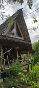 a house with a thatch roof with a porch at Bamboo hut Alpha Hotel in Maluk