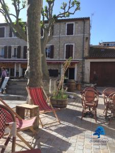 eine Terrasse mit Stühlen, einem Baum und einem Gebäude in der Unterkunft Mobilhome Le repaire du soleil in Sigean