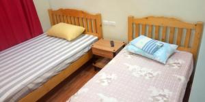two twin beds in a bedroom with a nightstand and a pillow at Hub Backpackers Hangout in Coron