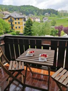 einen Holztisch mit zwei Schalen Tomaten auf dem Balkon in der Unterkunft Lavarone Gasperi 1 - Spazioso appartamento in Lavarone
