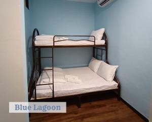 a room with two bunk beds in a blue room at Roxy Sematan Townhouse - Blue Lagoon in Sematan