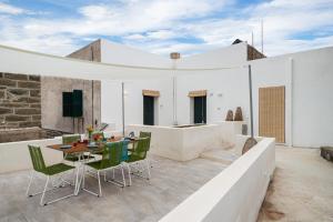 a white house with a patio with a table and chairs at Dammuso Mariù in Kamma